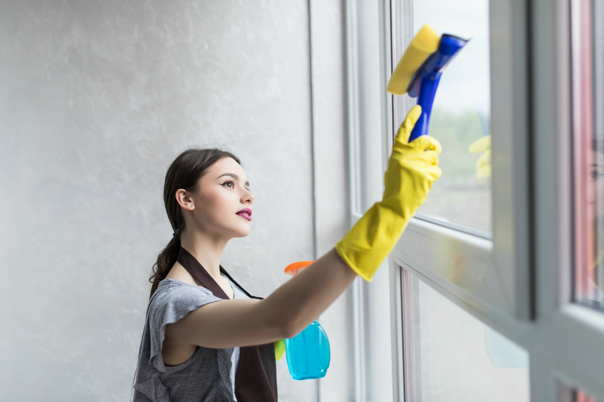 woman-protective-gloves-is-smiling-wiping-dust-using-spray-duster-while-cleaning-her-house-close-up
